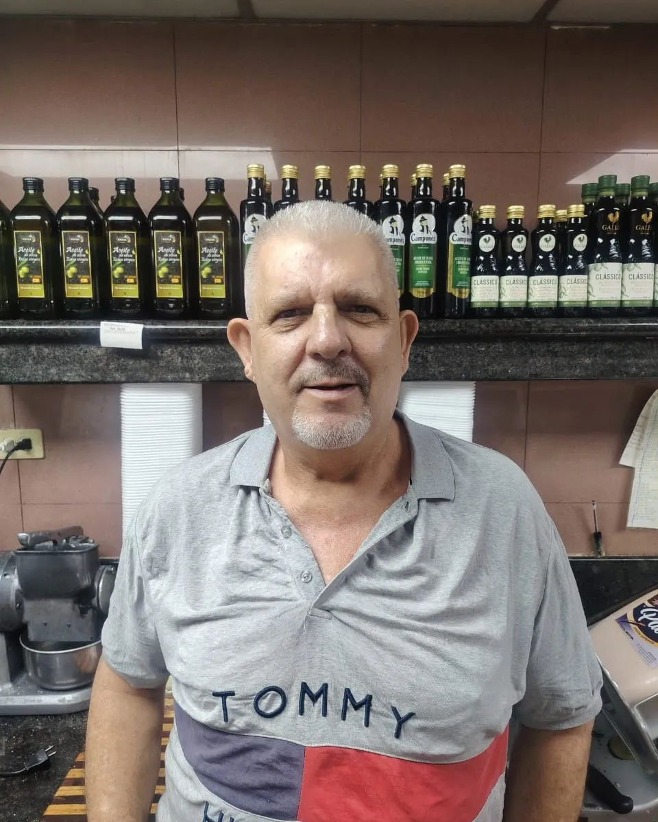 Bernardo Caldeira en su negocio, con los aceites en los estantes detrás de él